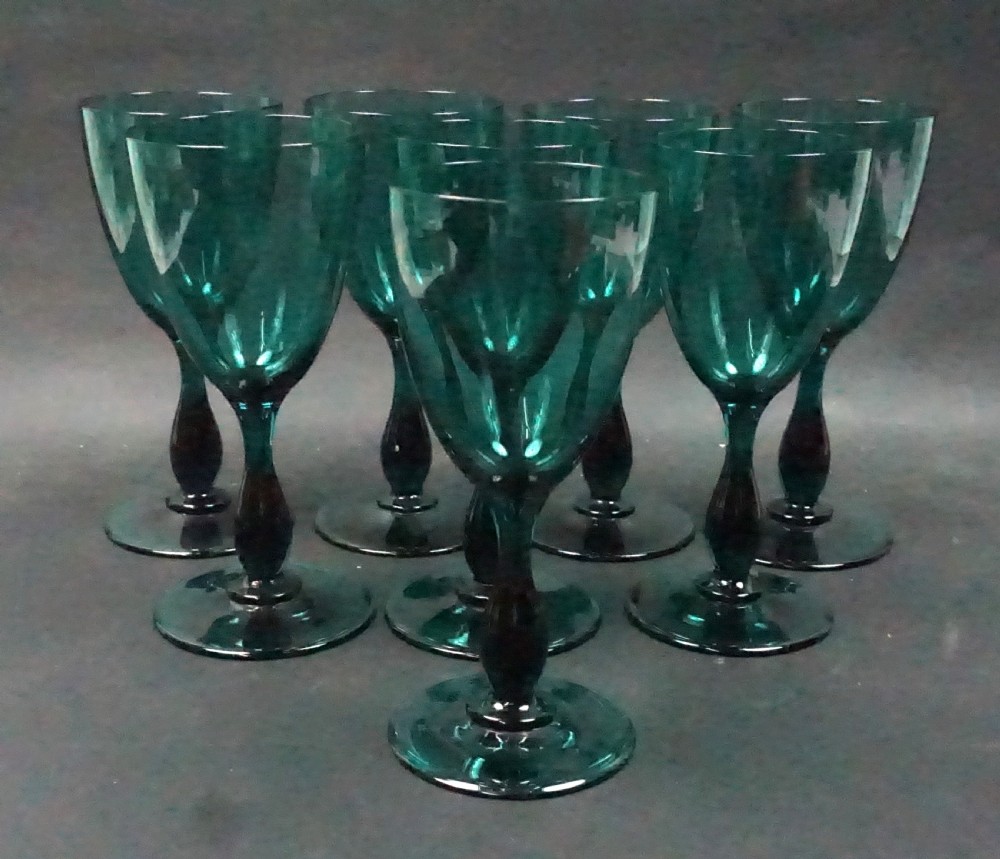 A set of eight emerald green tulip-shaped glass wine goblets with turned stems.