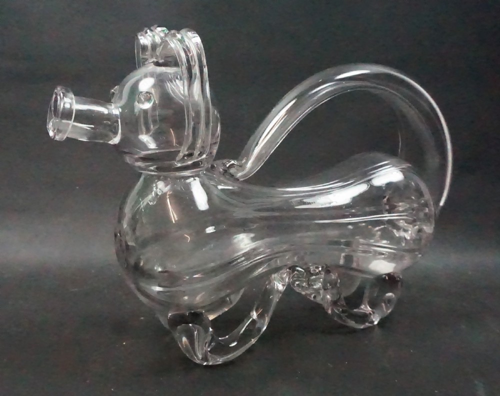 A clear hand-blown glass decanter sculpted in the shape of a dog with an integrated loop handle and snout spout.