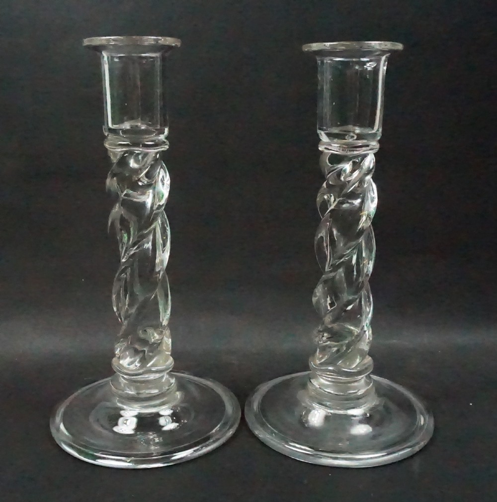 A pair of clear glass candlesticks featuring twisted spiral stems and round domed bases.