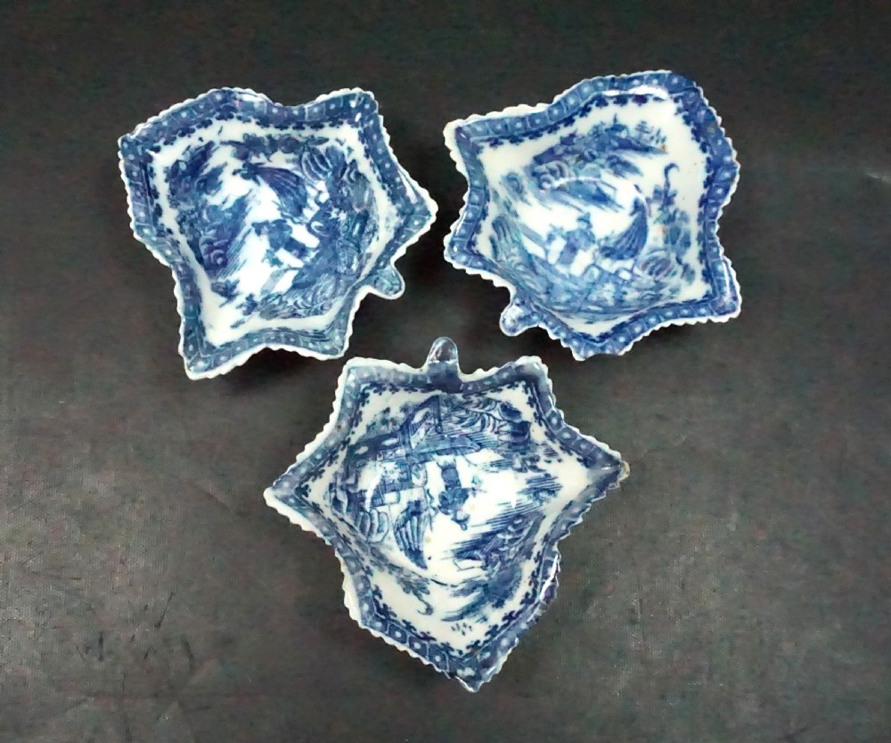 A set of three leaf-shaped blue and white Caughley porcelain pickle dishes featuring transfer-printed scenes of fishermen and cormorants.