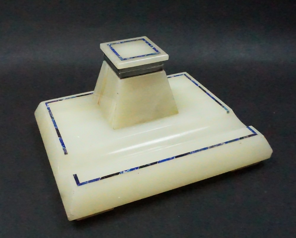 An Edwardian pale cream onyx inkstand featuring a central square inkwell with blue lapis lazuli inlay borders and silver mounts.