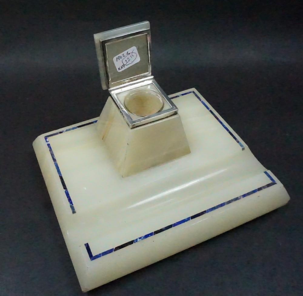An Edwardian pale cream onyx inkstand featuring a central square inkwell with blue lapis lazuli inlay borders and silver mounts. View II