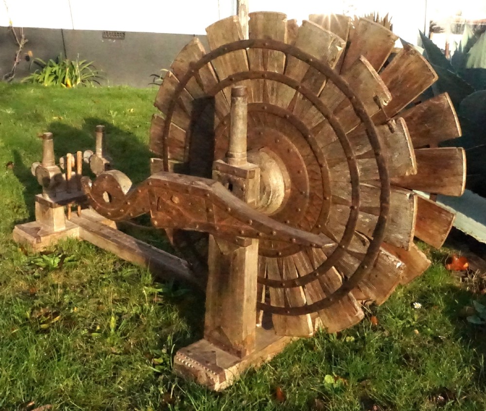 An early twentieth-century Indian oak charkha spinning wheel featuring a slatted drive wheel reinforced with iron bands on a low wooden base. View III