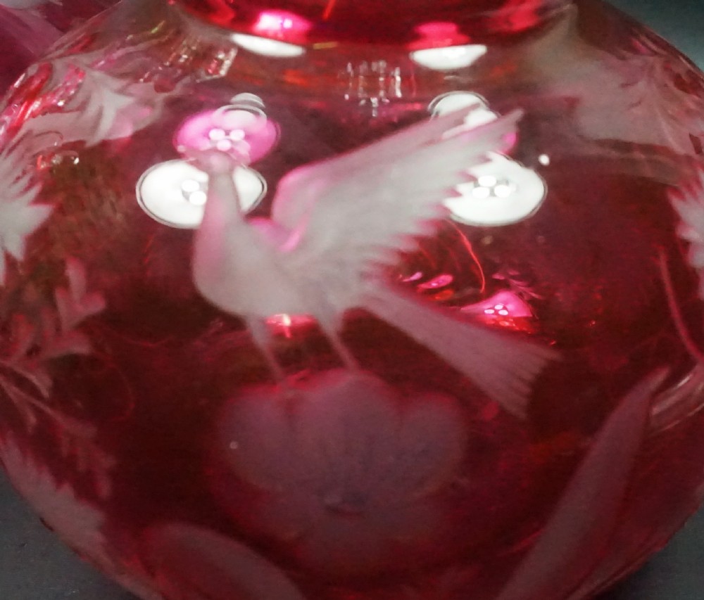 A pair of Victorian cranberry overlay glass decanters featuring cut stoppers and hand-engraved patterns of birds and grapevines. View II
