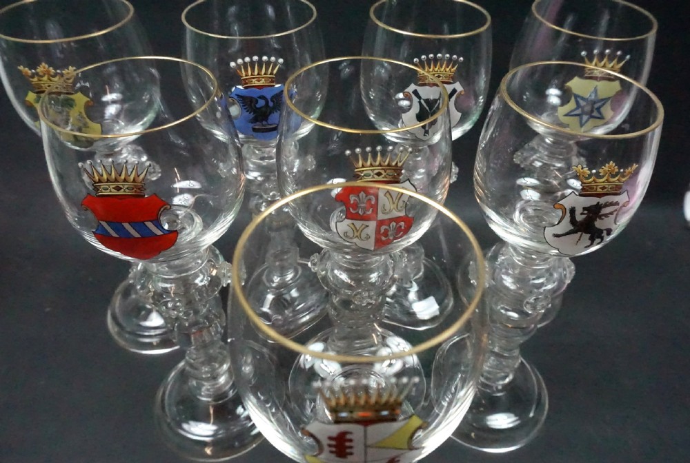 A group of eight clear glass roemer goblets decorated with colourful enamelled heraldic shields and gilded rims on knopped stems. View II