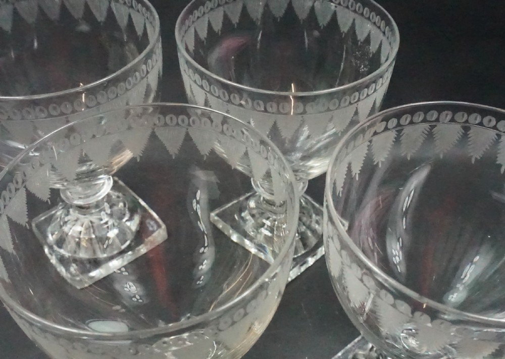A set of four clear antique crystal glass rummers featuring wheel-engraved bowls and square lemon squeezer moulded bases. View II