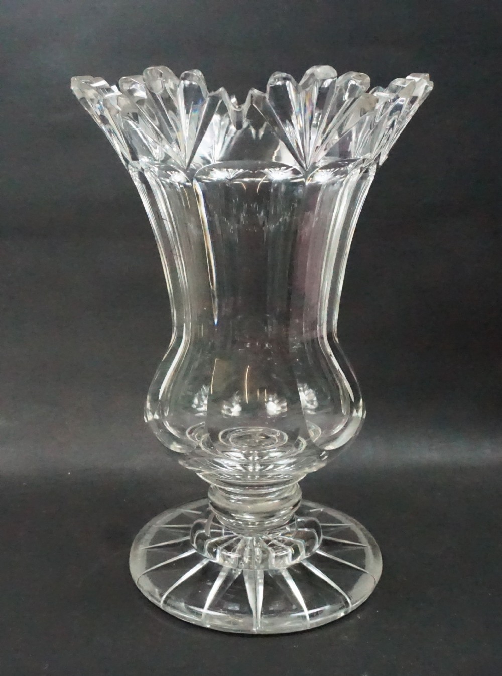 A Regency period clear lead crystal glass celery vase featuring a scalloped fan-cut rim, panel-cut sides, and a circular star-cut base.