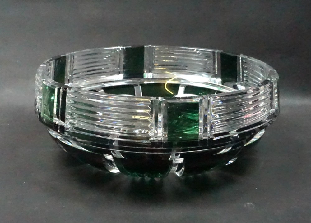 An Art Deco lead crystal bowl featuring dark green overlay glass hand-cut into geometric horizontal lines and rectangular panels.