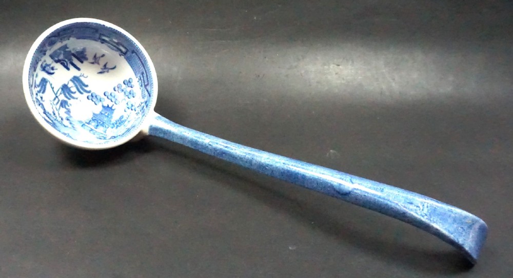An early Victorian blue and white transfer-printed ceramic soup ladle featuring a curved blue handle and chinoiserie patterned bowl.