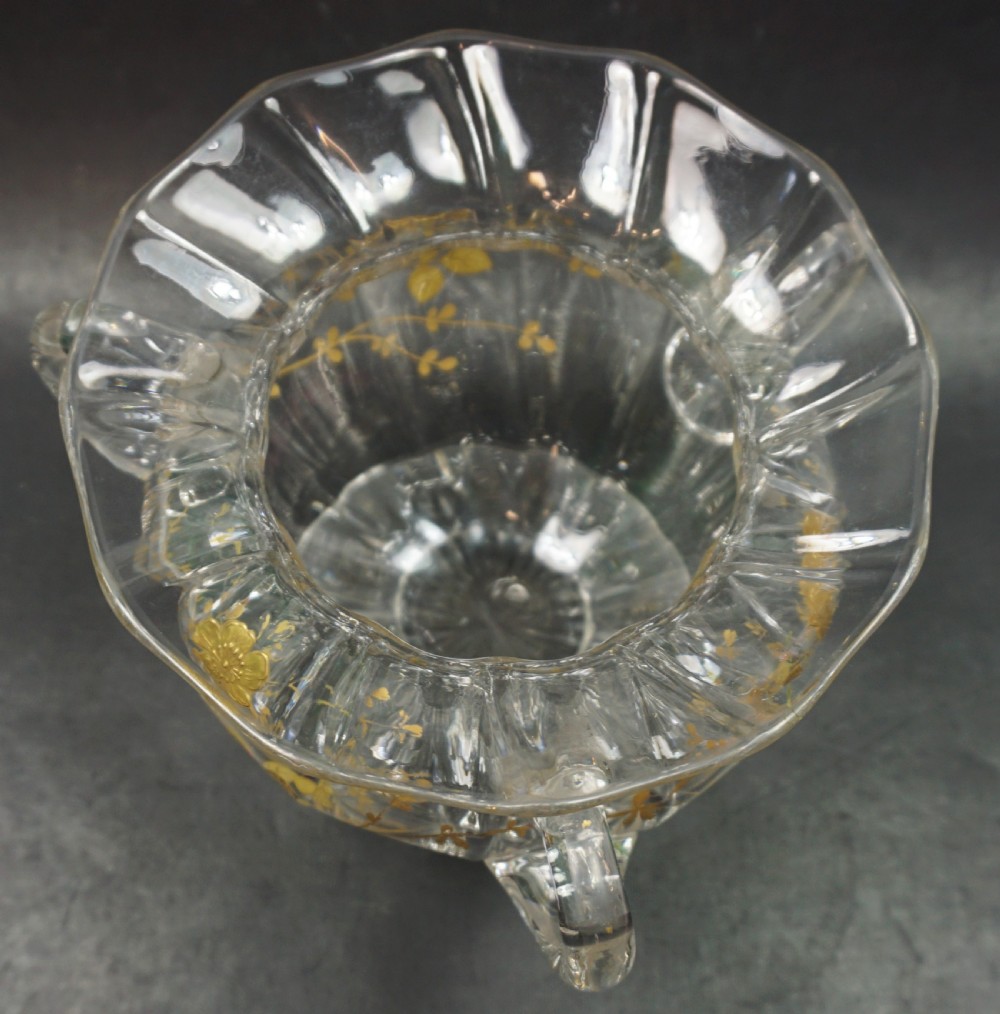 A clear cut crystal bowl featuring three applied handles, a flared scalloped rim, and gilt floral paste decoration around the body. View II