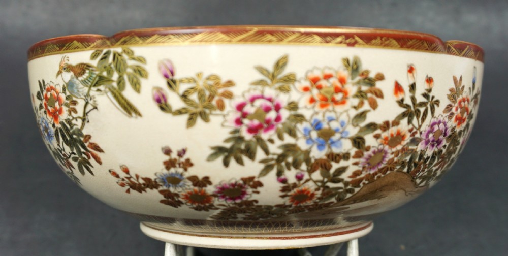 A Japanese ceramic Satsuma bowl with a lobed rim, decorated with hand-painted birds, flowers, and a landscape scene on a cream crackle-glazed interior. View III