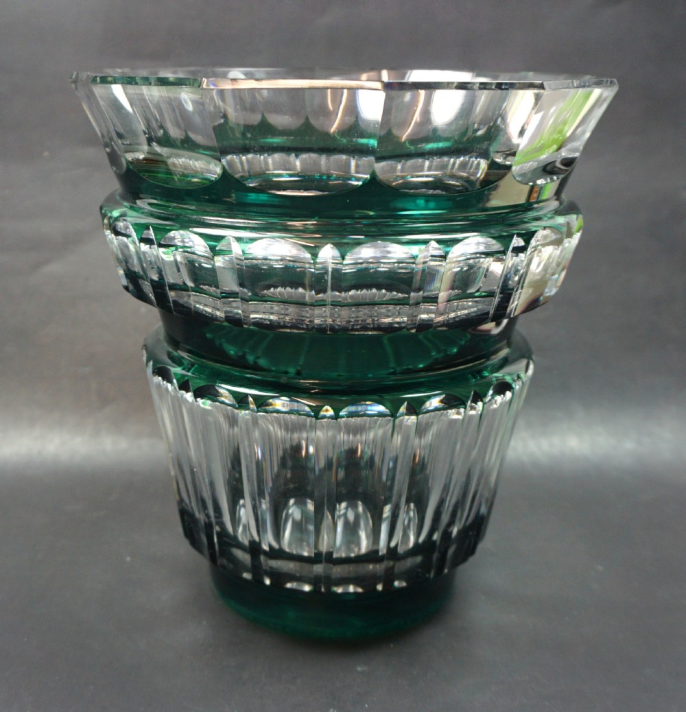 A heavy Art Deco glass vase featuring an emerald green overlay cut into geometric facets over clear lead crystal.