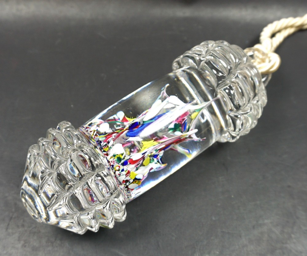 A cylindrical Victorian clear glass bell pull featuring internal multicoloured glass spatter inclusions, moulded faceted end caps, and a suspended twisted rope cord.