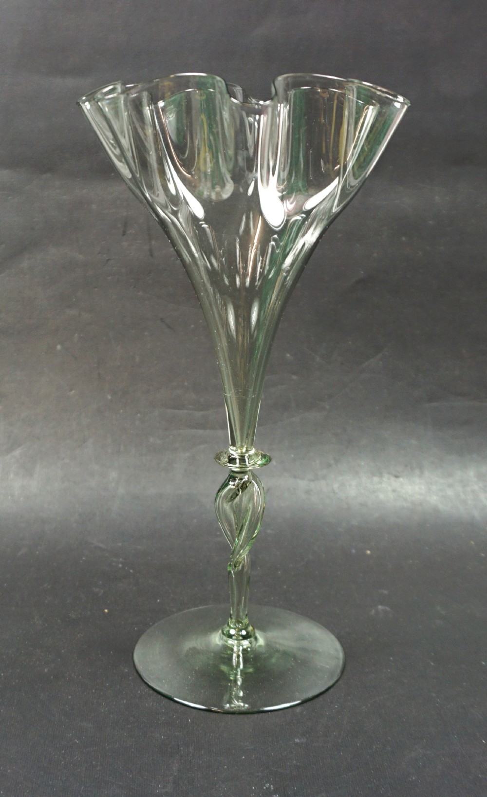 A tall pale green hand-blown glass vase featuring a scalloped rim, a twisted stem, and a circular flat foot.