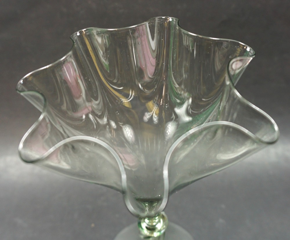 A tall pale green hand-blown glass vase featuring a scalloped rim, a twisted stem, and a circular flat foot. View II