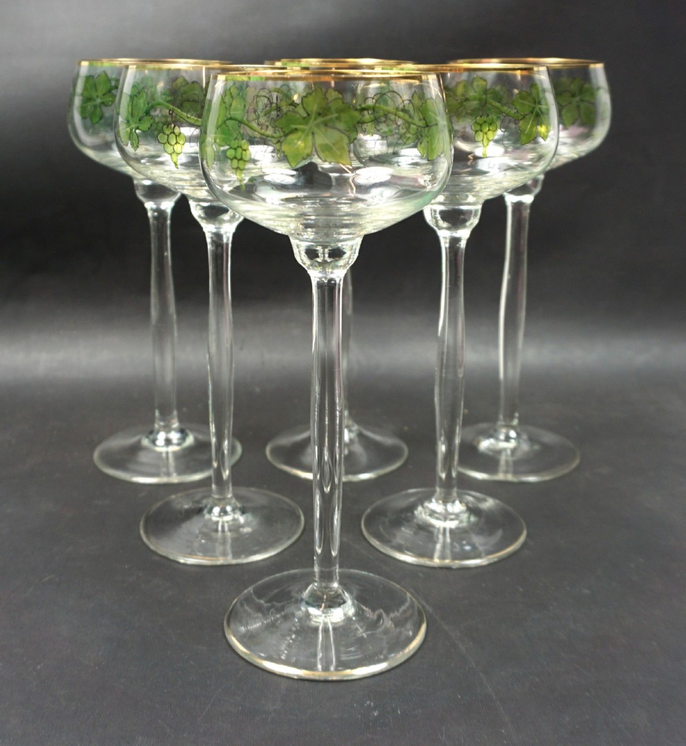A set of six tall clear crystal hock glasses decorated with green enamelled grapevine motifs and gilded rims.