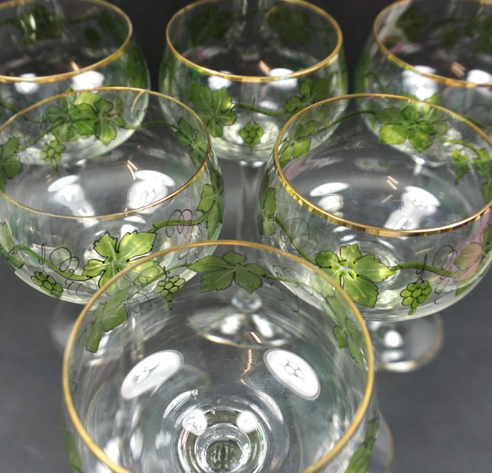 A set of six tall clear crystal hock glasses decorated with green enamelled grapevine motifs and gilded rims. View II