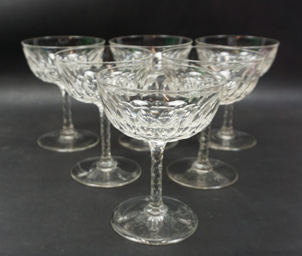 A set of six clear Victorian cut-crystal champagne coupes featuring shallow wide bowls and facet-cut stems.