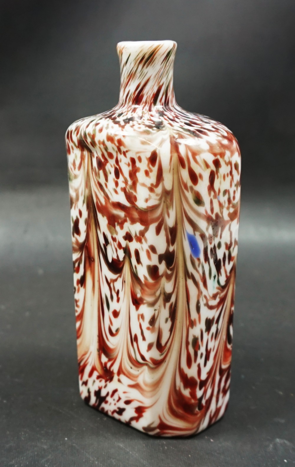 An 18th-century rectangular milk glass flask featuring a white opaque body decorated with marbled reddish-brown spatter patterns and a short narrow neck.