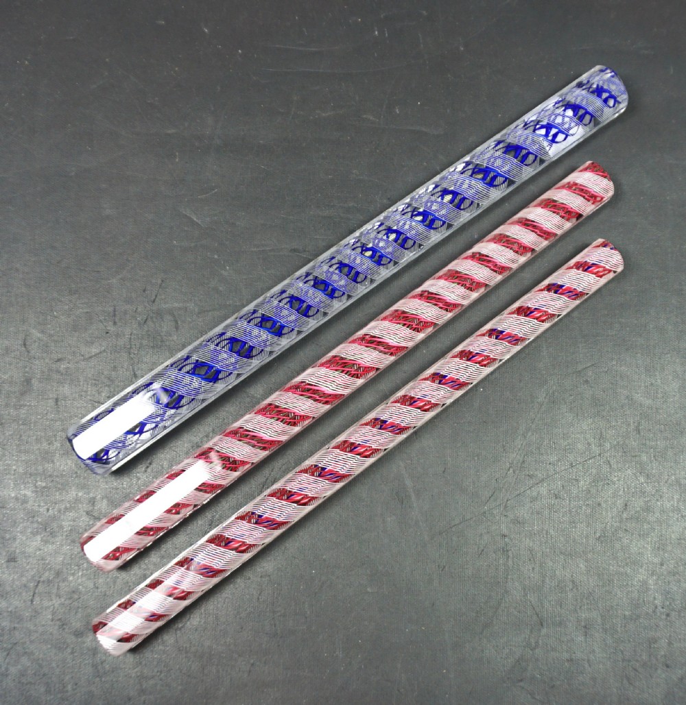 Three facet-cut clear crystal glass rulers featuring internal spiralled red, blue, and white filigree twists.