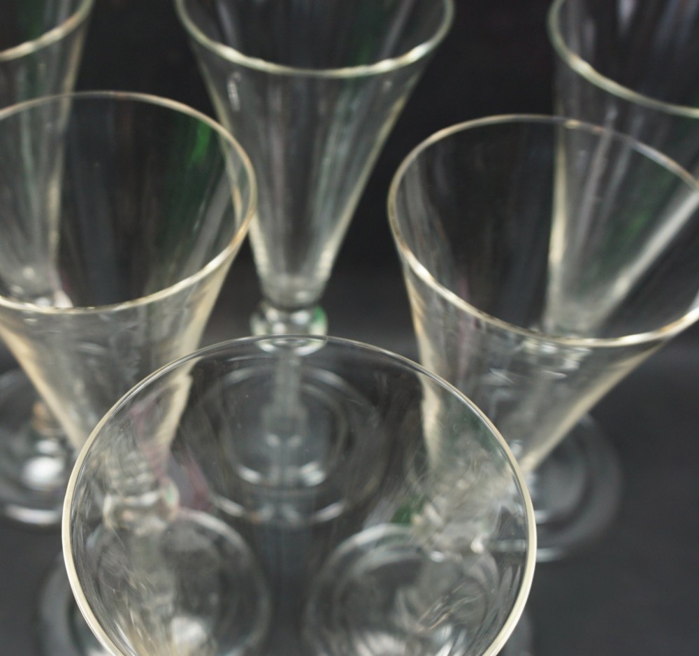 A set of six tall clear glass flutes with conical bowls, knopped air twist stems, and circular bases. View II