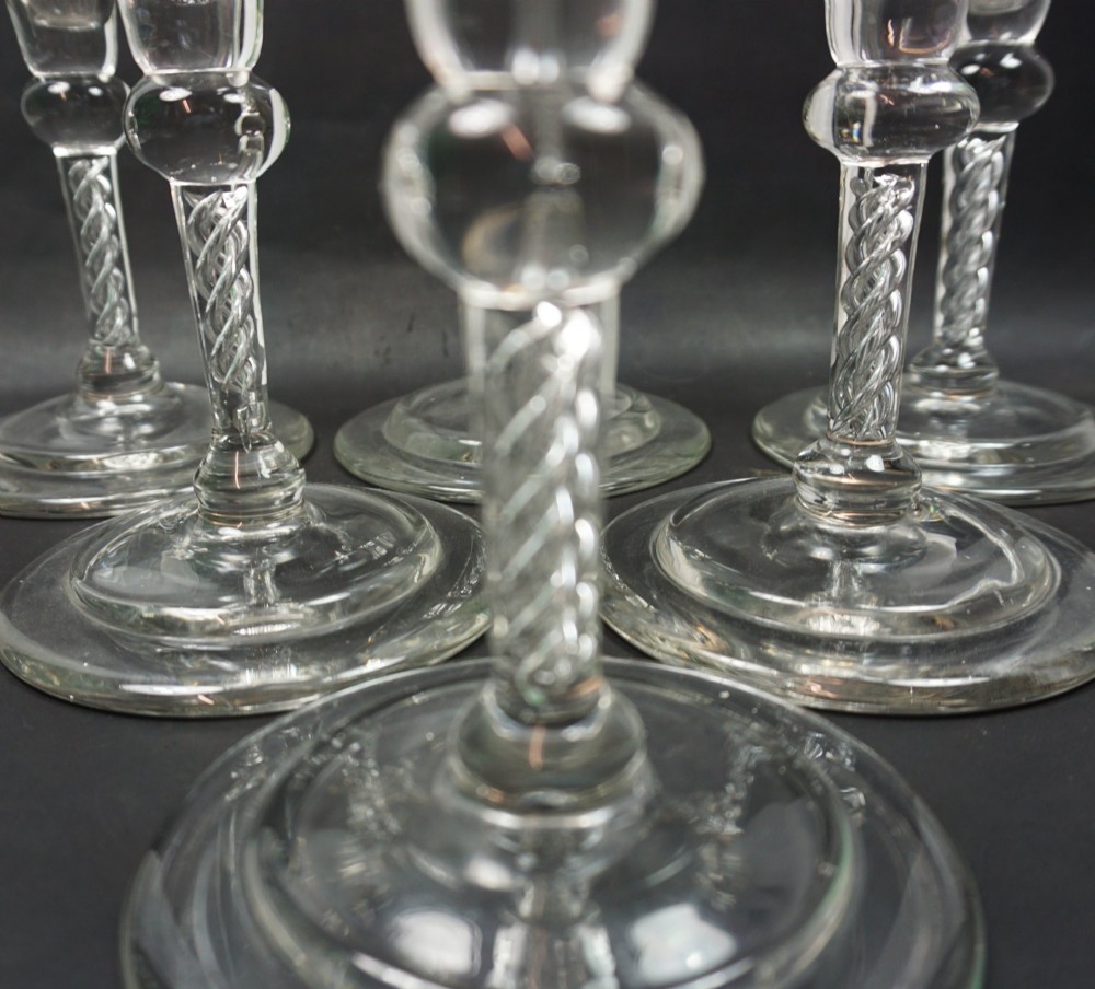 A set of six tall clear glass flutes with conical bowls, knopped air twist stems, and circular bases. View III