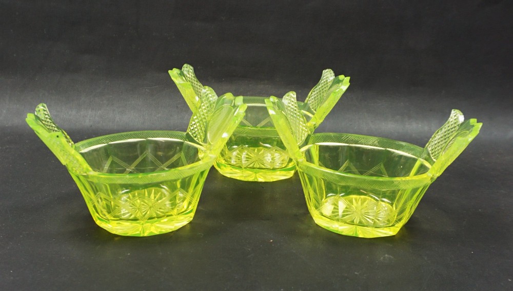 A nineteenth-century Bohemian yellow-green uranium glass dish featuring hand-cut geometric facets, diamond cross-hatching, and two flared wing-like handles. View III