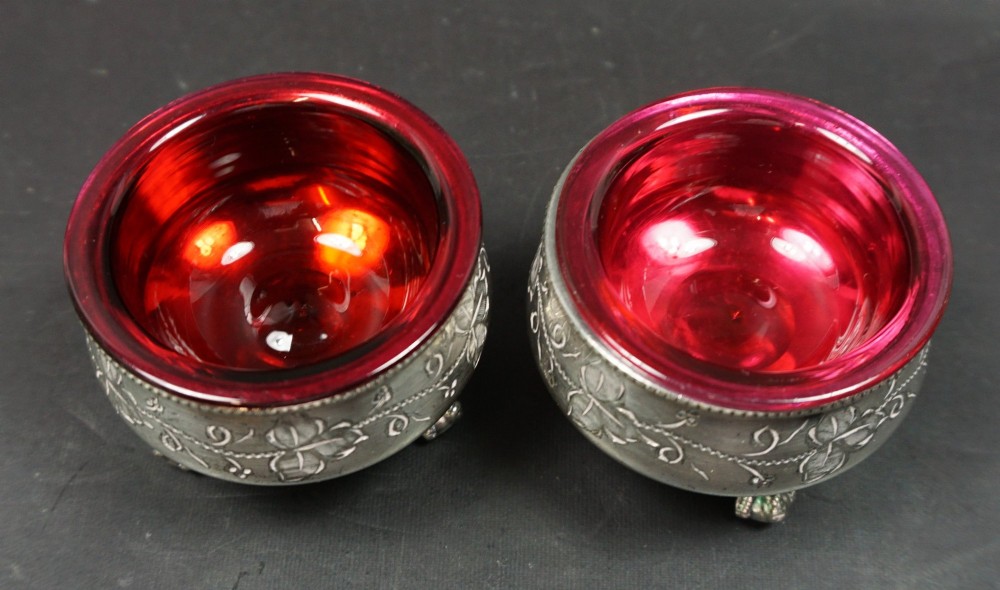 A pair of Victorian silver-plated open salt cellars with chased ivy leaf decoration and vibrant red cranberry glass liners. View II
