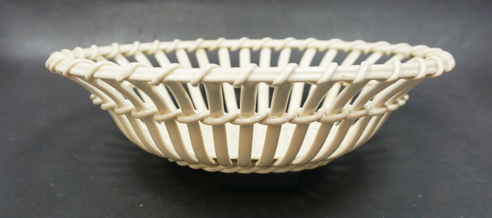 An antique creamware ceramic basket featuring openwork lattice construction imitating woven cane with a solid circular base. View II