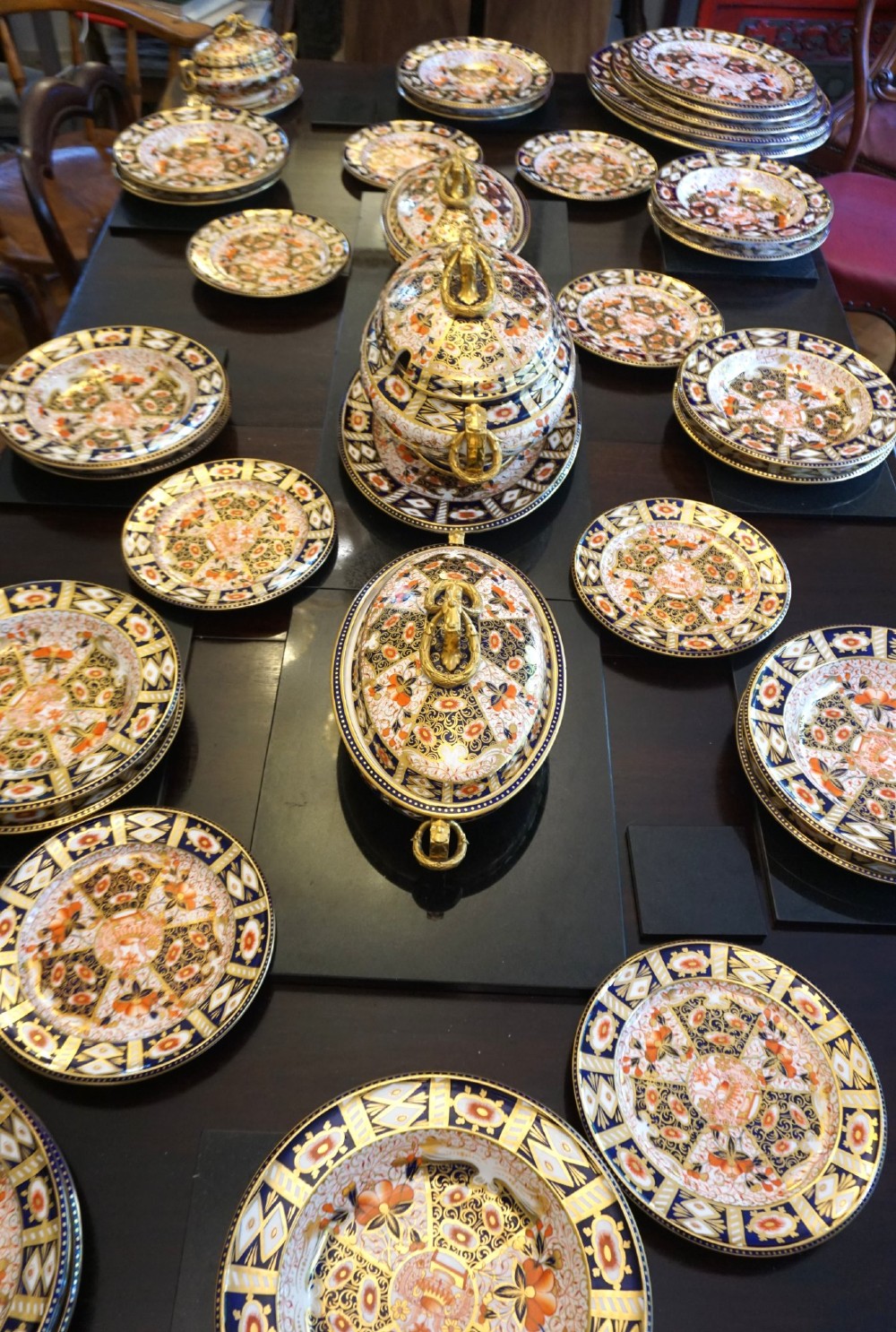An extensive Victorian Davenport Imari pattern porcelain dinner service comprising numerous plates, serving platters, and covered tureens decorated in cobalt blue, orange, and gilt.