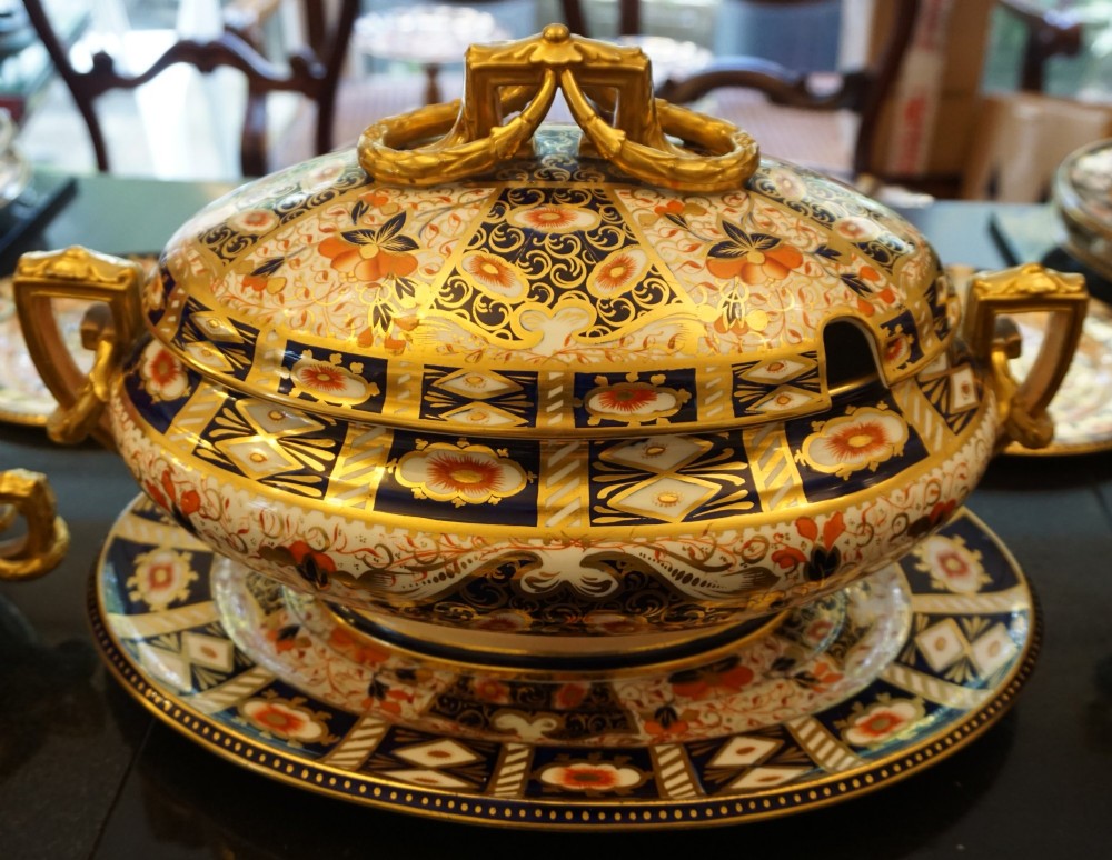 An extensive Victorian Davenport Imari pattern porcelain dinner service comprising numerous plates, serving platters, and covered tureens decorated in cobalt blue, orange, and gilt. View VI