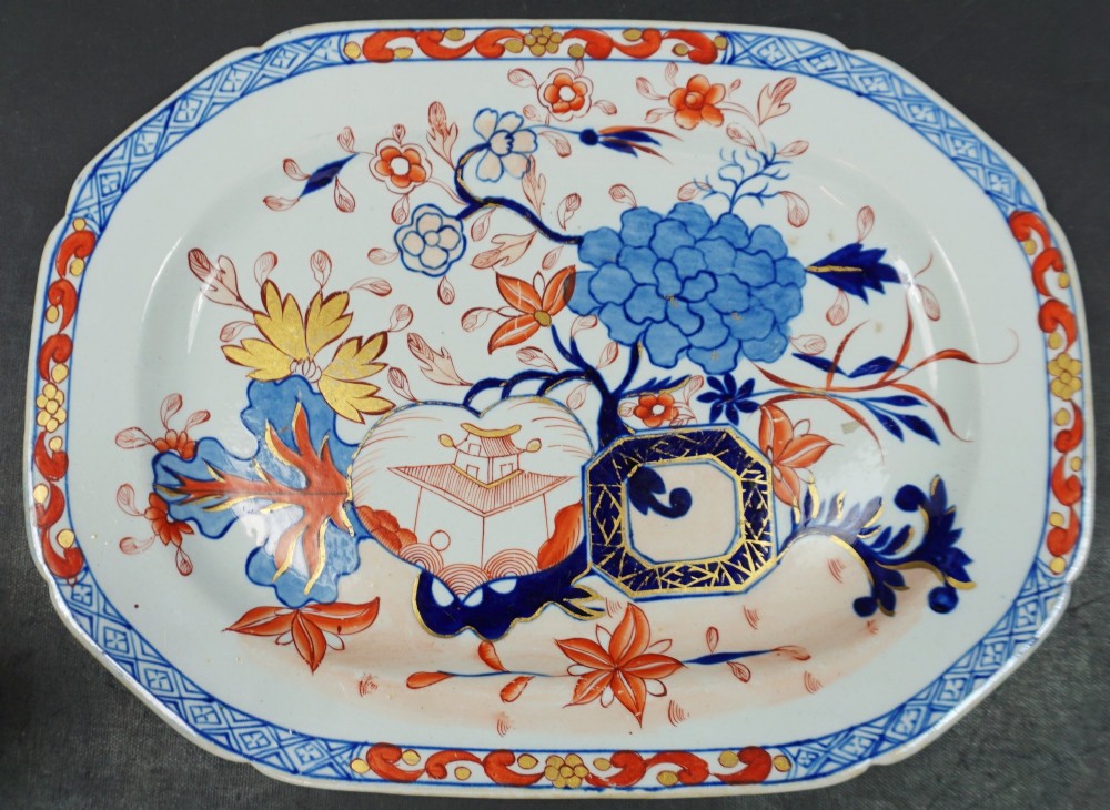 An oval Regency period Masons ironstone ceramic platter decorated with hand-coloured Chinoiserie floral patterns, gold accents, and a blue and orange geometric rim.