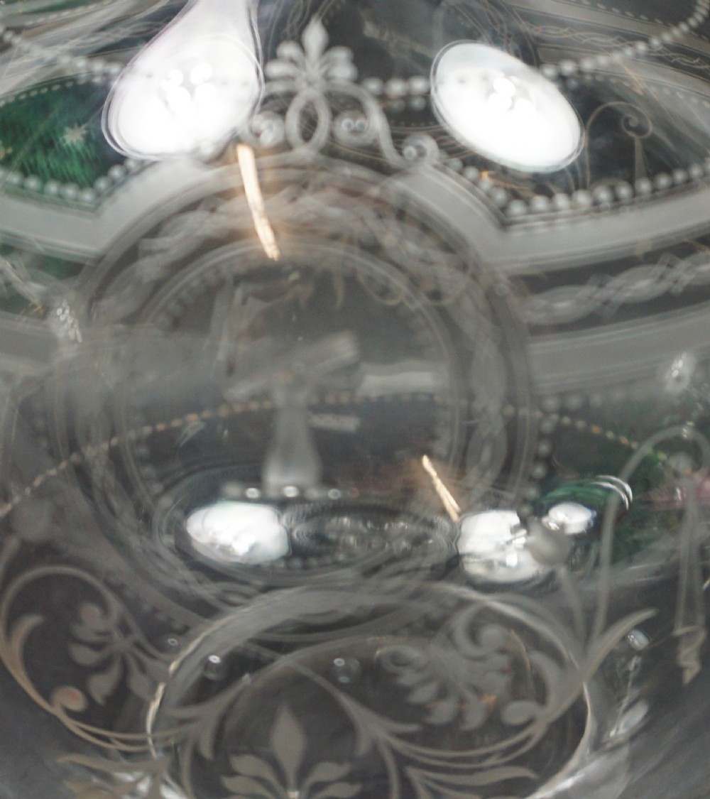 An antique clear glass wine decanter featuring wheel-engraved heraldic crests, a rounded loop handle, and a matching spherical stopper. View II