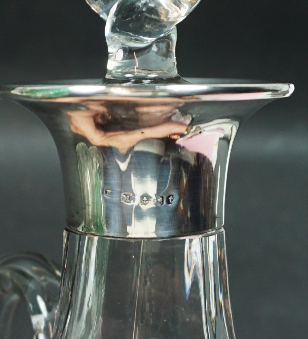 A clear crystal glass decanter featuring dark green applied leaf mouldings around the lower body, a loop handle, a silver collar, and a twisted cut-glass stopper. View II