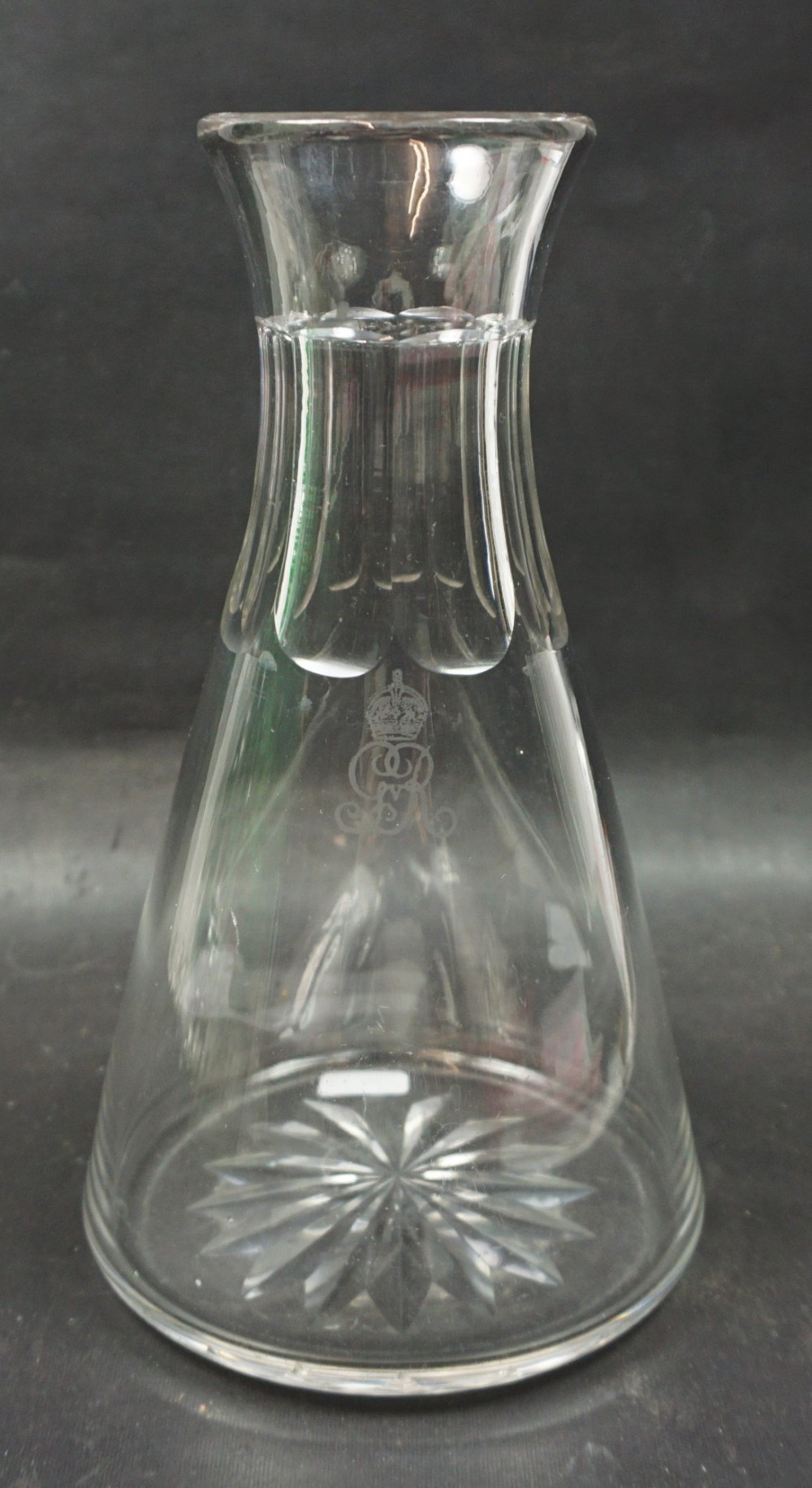 A clear glass carafe featuring a flared base with starburst cutting, fluted neck panels, and an etched Royal Cypher monogram beneath a crown.