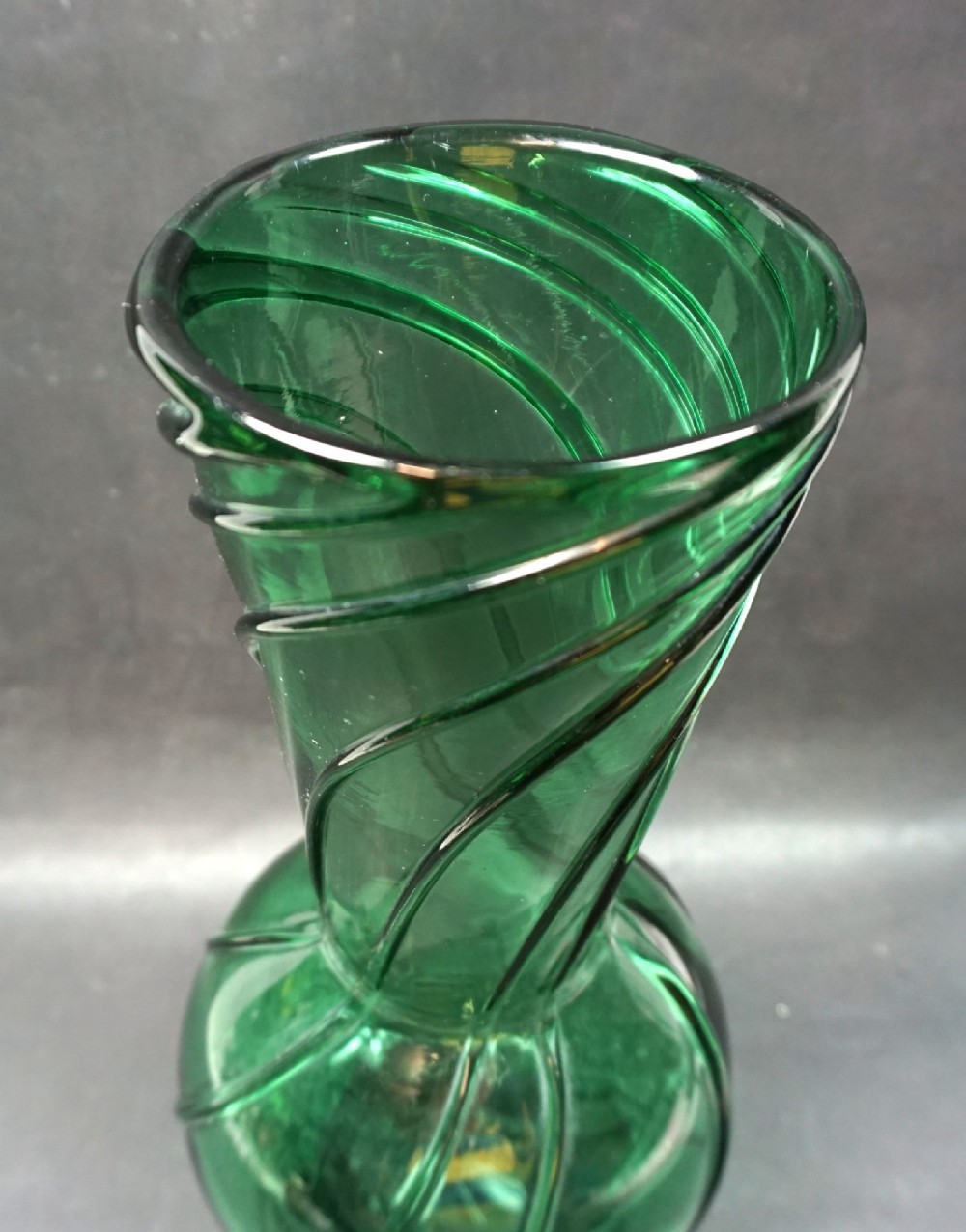 A translucent green hand-blown glass vase featuring a twisted wrythen rib pattern, a bulbous lower section, and a flared rim. View II