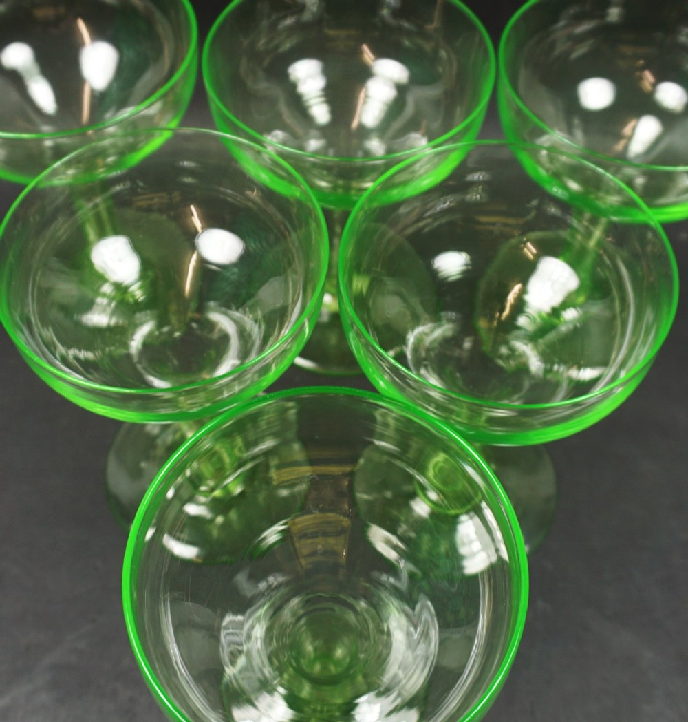 A set of six bright green uranium glass champagne coupes featuring hollow stems and circular bases. View II