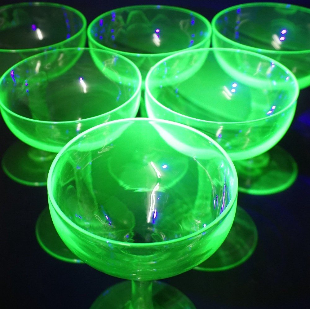 A set of six bright green uranium glass champagne coupes featuring hollow stems and circular bases. View III