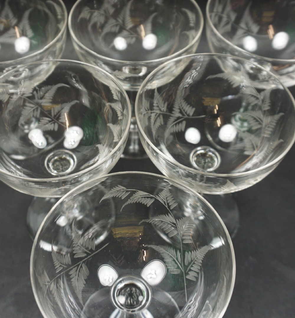 A set of six clear crystal champagne coupes with etched fern leaf motifs on shallow circular bowls and slender stems. View II