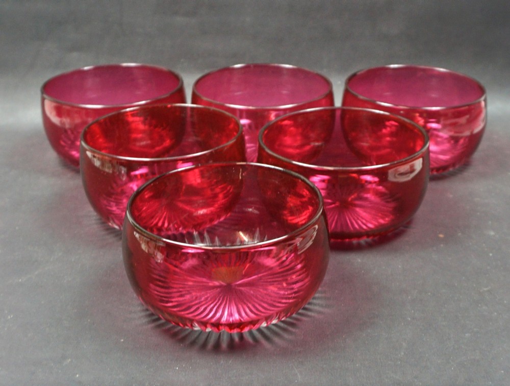 A set of six Victorian red overlay crystal glass finger bowls featuring cut starburst patterns on the bases.