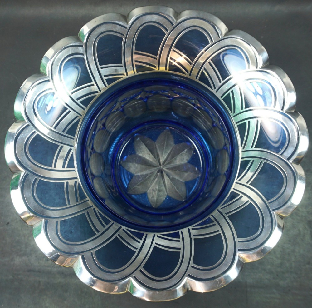 A cobalt blue cut crystal bowl featuring a flared scalloped rim decorated with geometric silver overlay arches and circular lens cuts around the lower body. View II