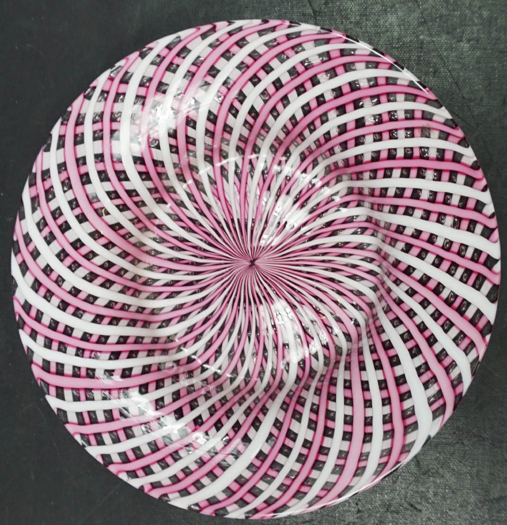 A circular Victorian glass plate featuring an intricate spiral lattice pattern formed from alternating pink and white opaque canes.