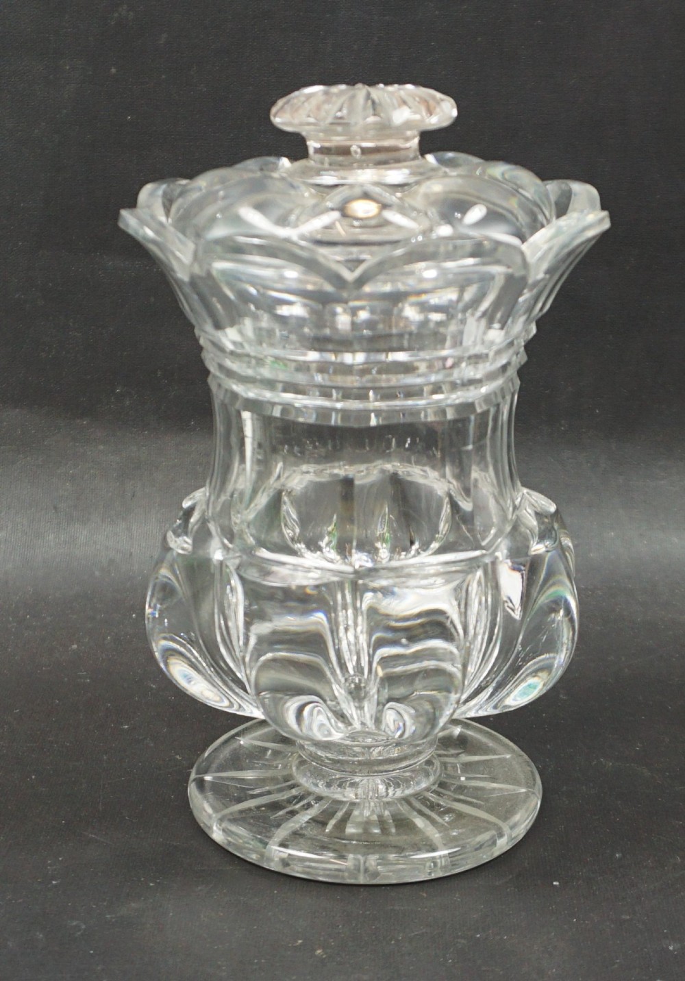 A clear cut crystal preserve jar with a fitted lid, pillar-moulded body, and a star-cut circular foot.