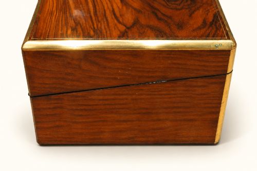 fig 1. A rectangular Victorian rosewood writing slope featuring brass-bound edges, an inlaid central brass plaque, and a key with a tassel in a brass Bramah lock.