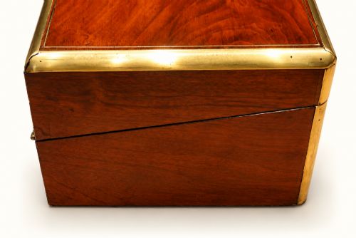 fig 1. A rectangular Victorian walnut writing slope box featuring polished brass edge binding, a central brass inlaid plaque, and a key inserted into the front lock.