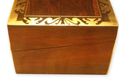 fig 1. A closed rectangular dark rosewood writing slope box featuring detailed brass foliate inlay along the borders and a brass key inserted into the front lock.