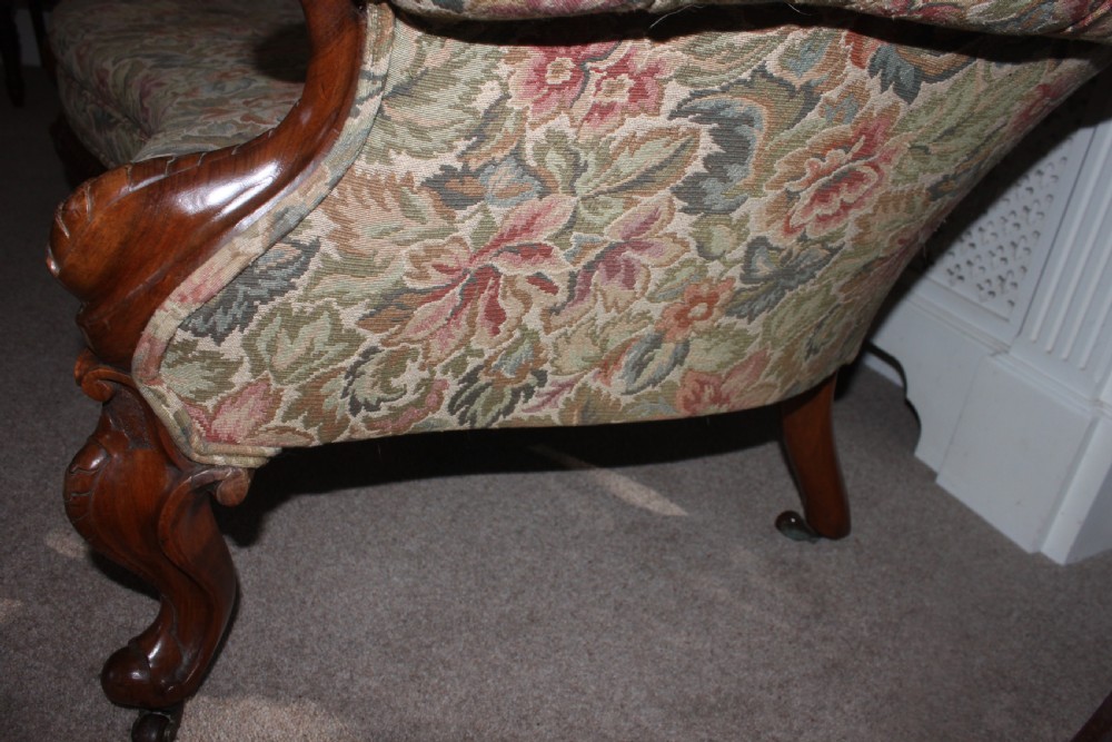 A Victorian carved walnut settee featuring button-tufted floral tapestry upholstery and scrolled wooden legs. View IX