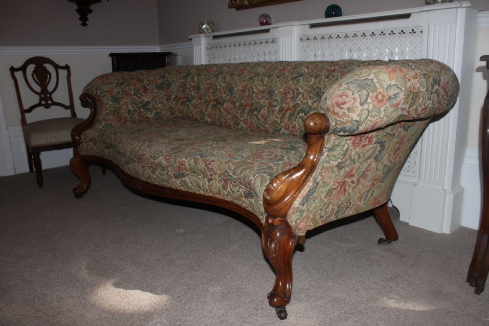 A Victorian carved walnut settee featuring button-tufted floral tapestry upholstery and scrolled wooden legs. View X