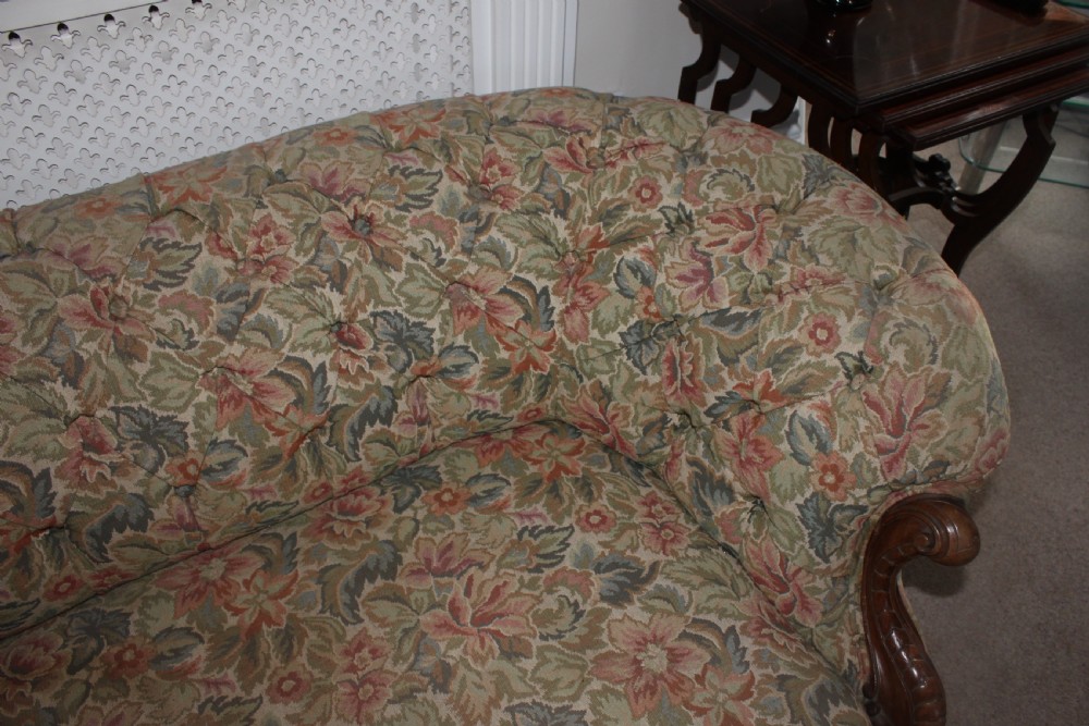 A Victorian carved walnut settee featuring button-tufted floral tapestry upholstery and scrolled wooden legs. View XVII