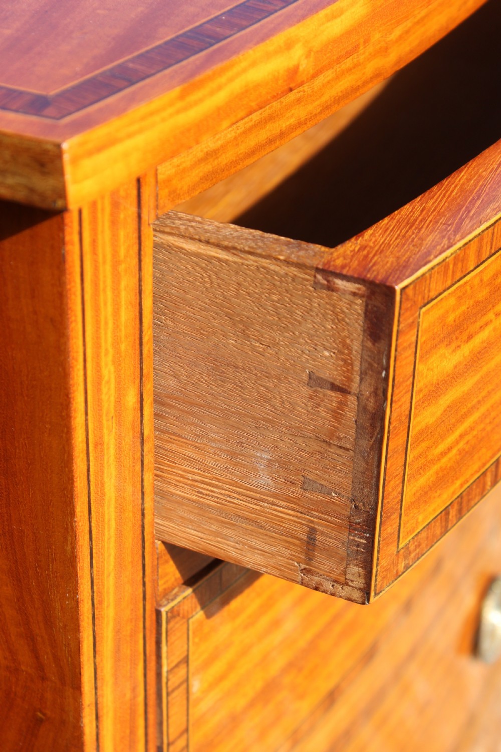 A tall Sheraton Revival satinwood bow front chest featuring six drawers with inlaid crossbanded borders, central brass ring handles, and splayed bracket feet. View VI